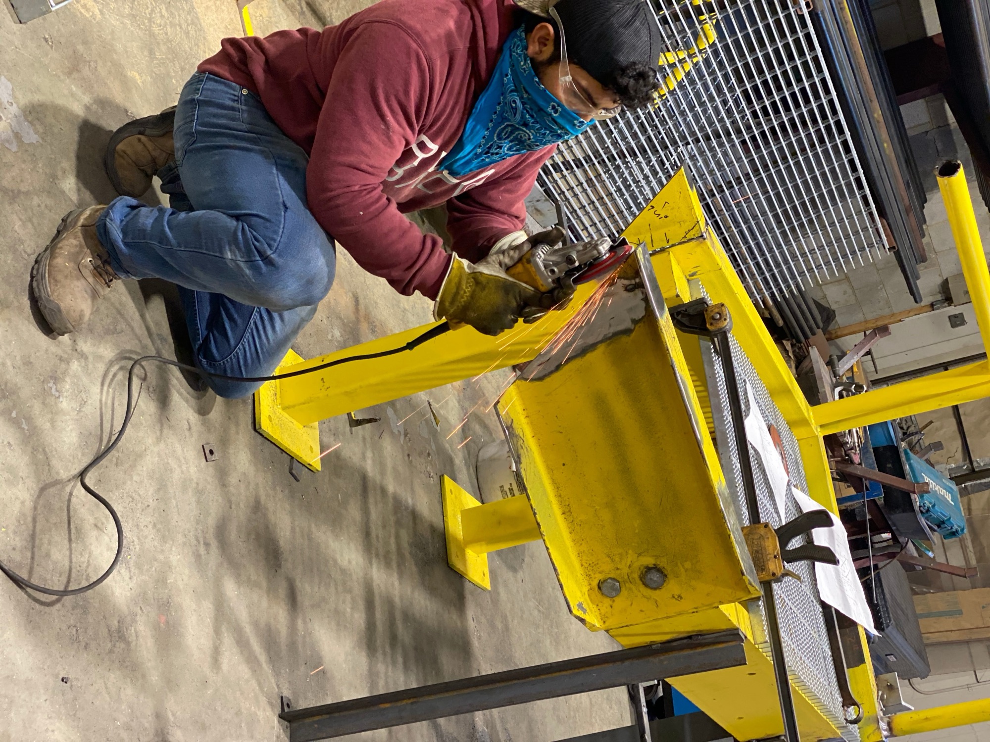 GWC fabricator welding a yellow steel assembly on the shop floor